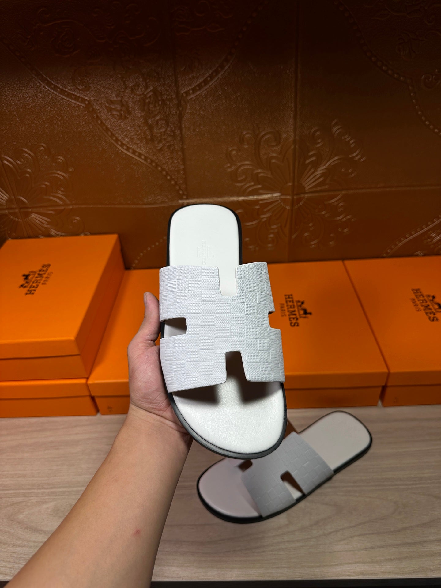 Hermes white slide sandals held in hand, textured strap and open-toe design