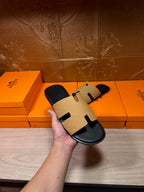 Hermes beige and black slide sandal held in hand, open toe