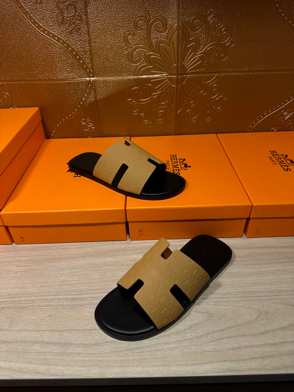 Hermes beige and black slide sandals on orange box, side profile