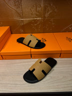 Hermes beige and black slide sandals on orange box, side profile