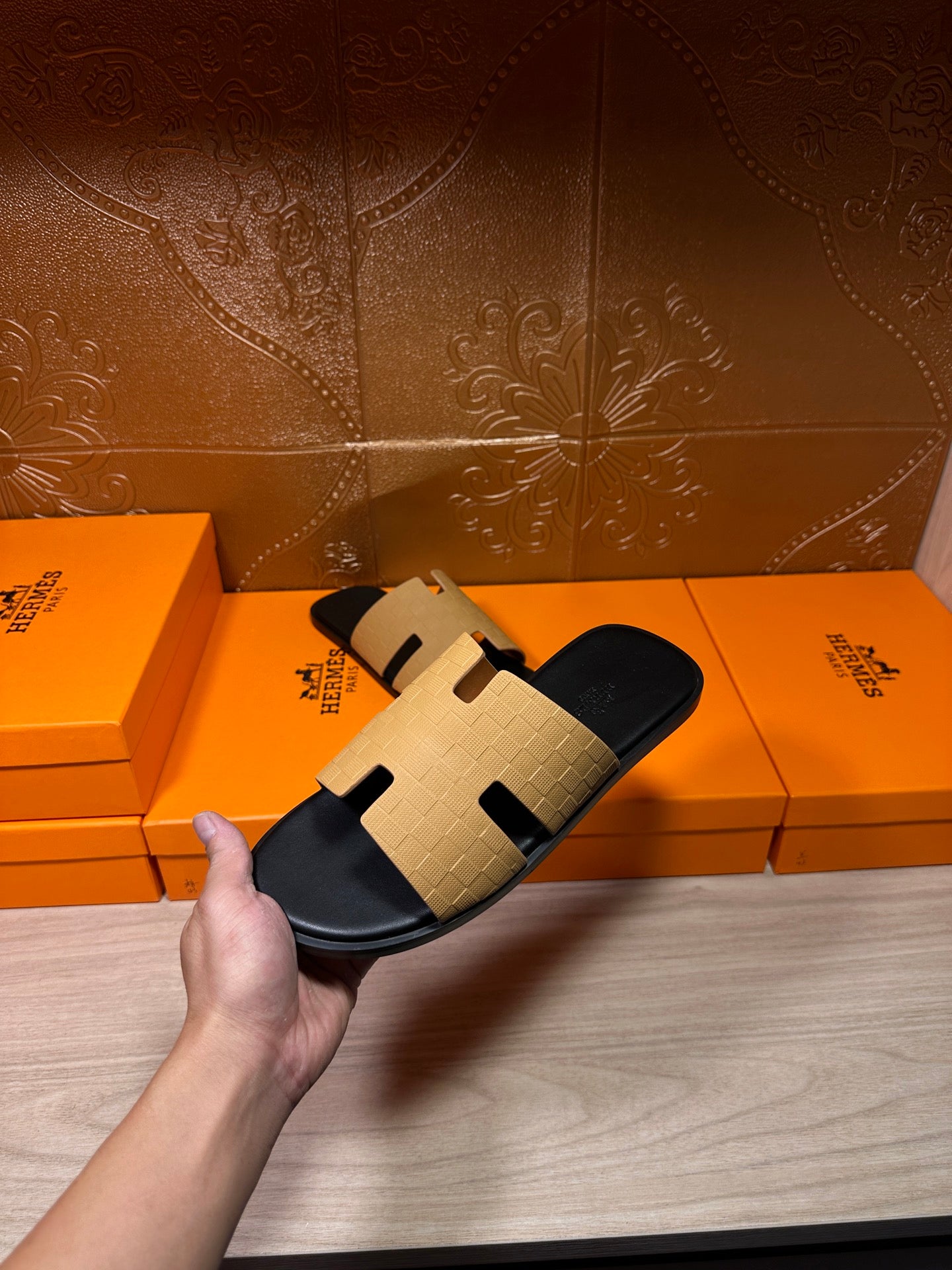 Hermes beige and black slide sandal held above box, open toe