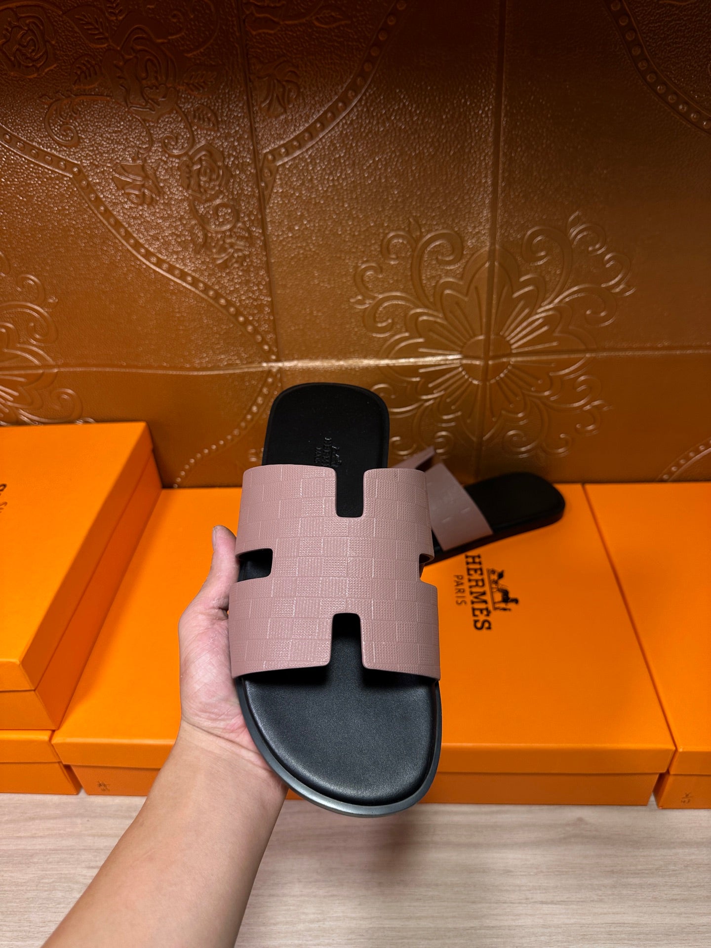 Hand holding black slide sandal featuring a light gray wide strap and open-toe cutout
