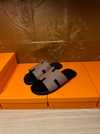 Black slide sandals with light gray wide strap across the foot and open-toe silhouette