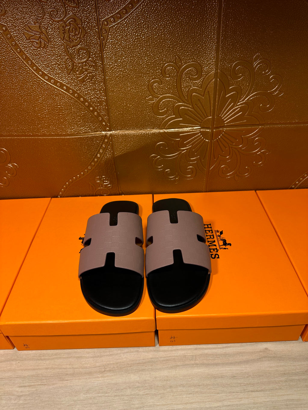 Pair of black slide sandals with light gray wide H-style strap and open-toe design