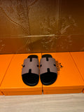 Pair of black slide sandals with light gray wide H-style strap and open-toe design