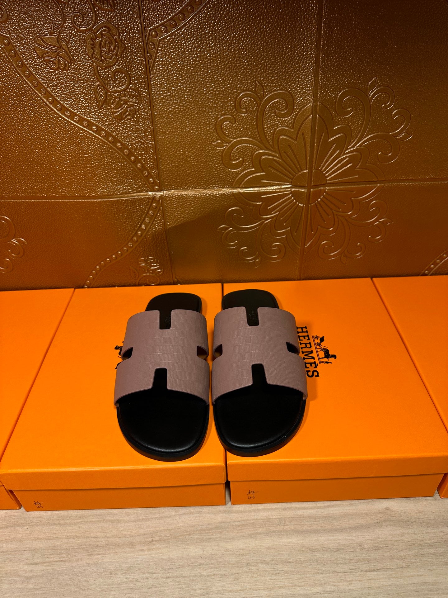 Pair of black slide sandals with light gray wide H-style strap and open-toe design