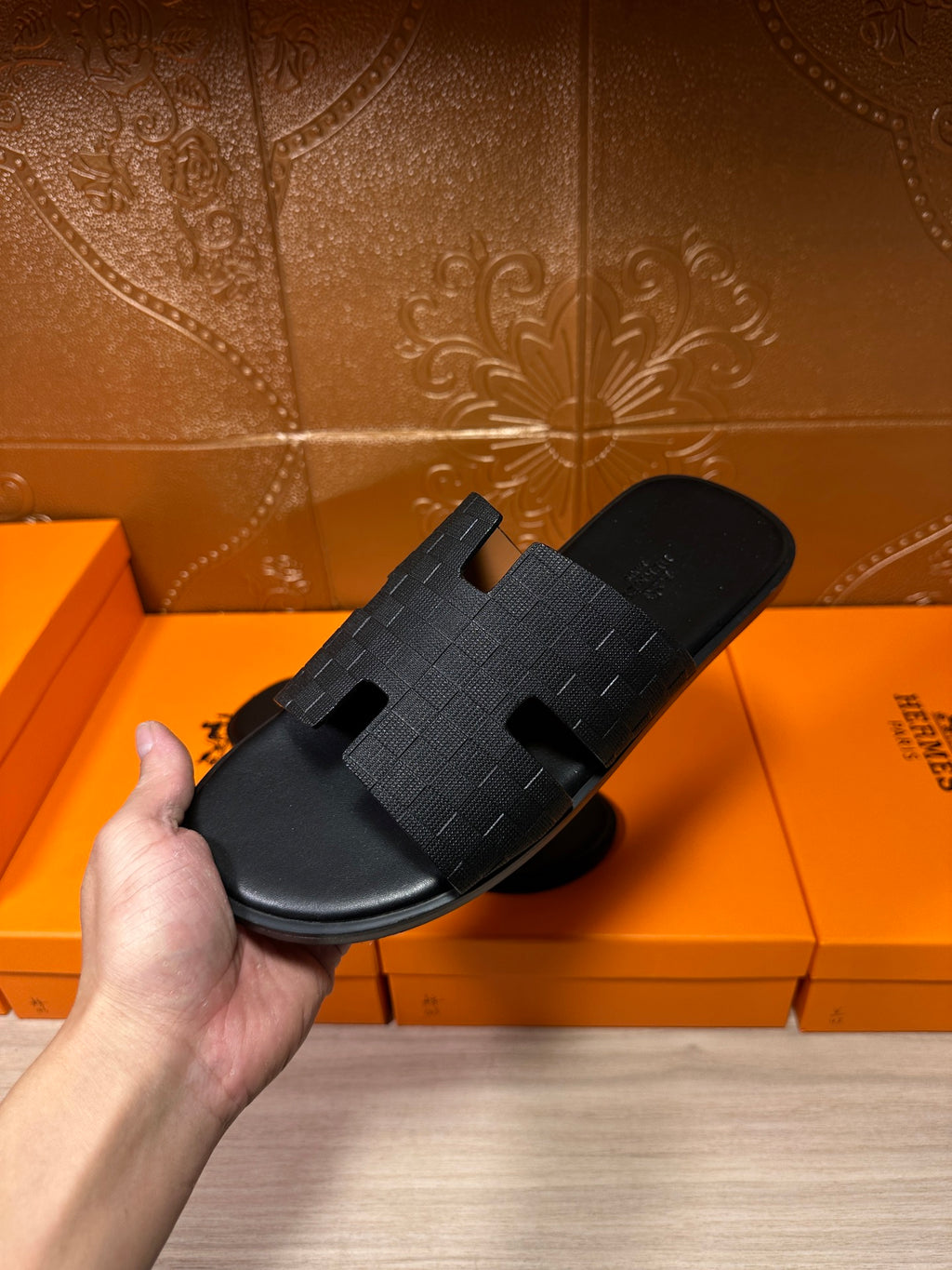 Black slide sandal held in hand with textured crossover strap and open toe
