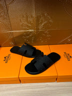 Black slide sandals pair with textured straps and open toe
