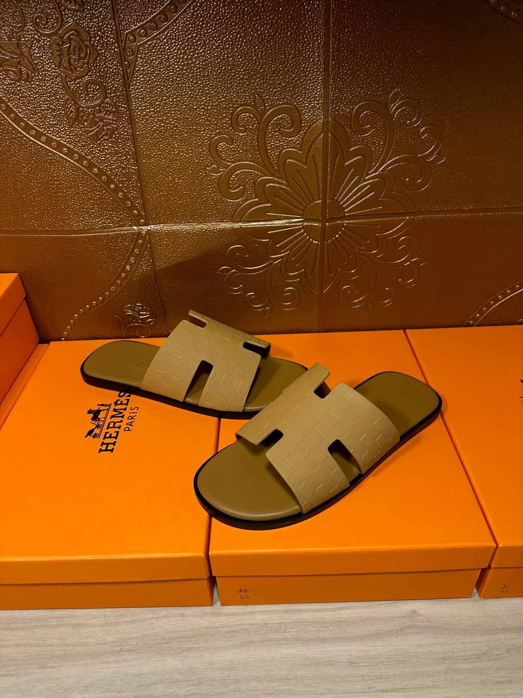 Beige slide sandals on orange shoeboxes, open toe with embossed straps