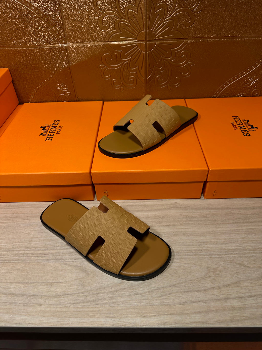 Beige slide sandals with open toe, laid down near shoeboxes