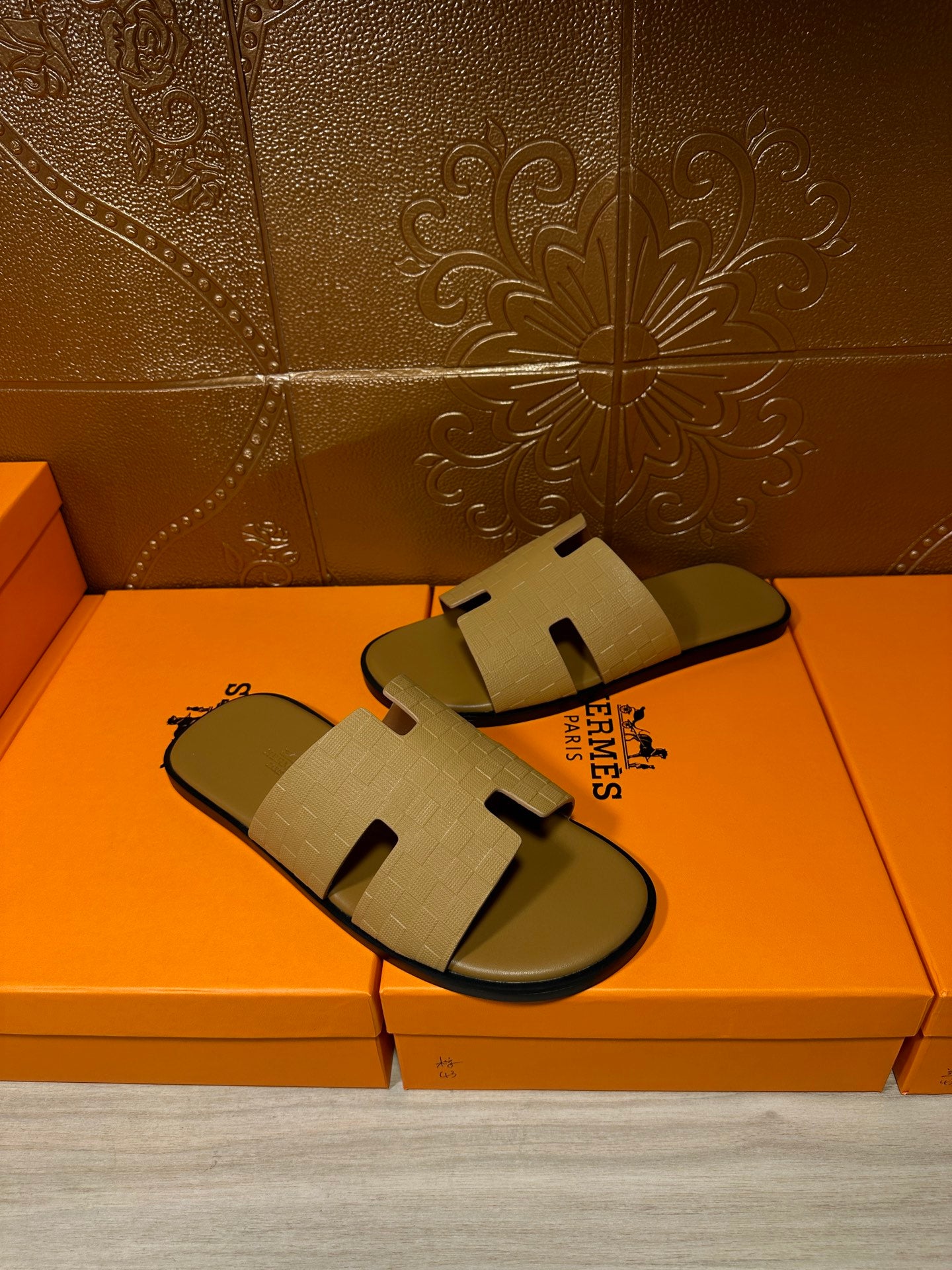 Beige slide sandals held together, textured cross-strap upper and dark sole