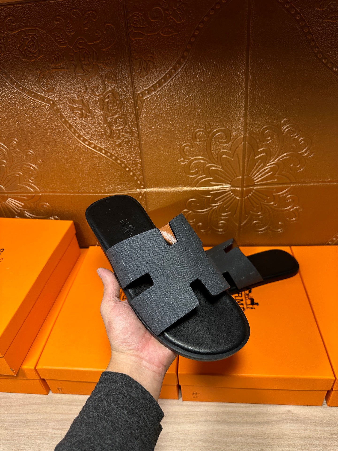 Hermes dark blue slide sandal being held, textured molded H strap on black sole