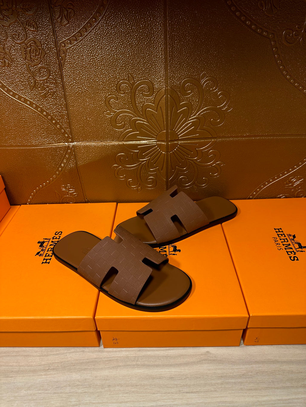 Hermes slide sandals with tan straps and open-toe cutouts on retail box