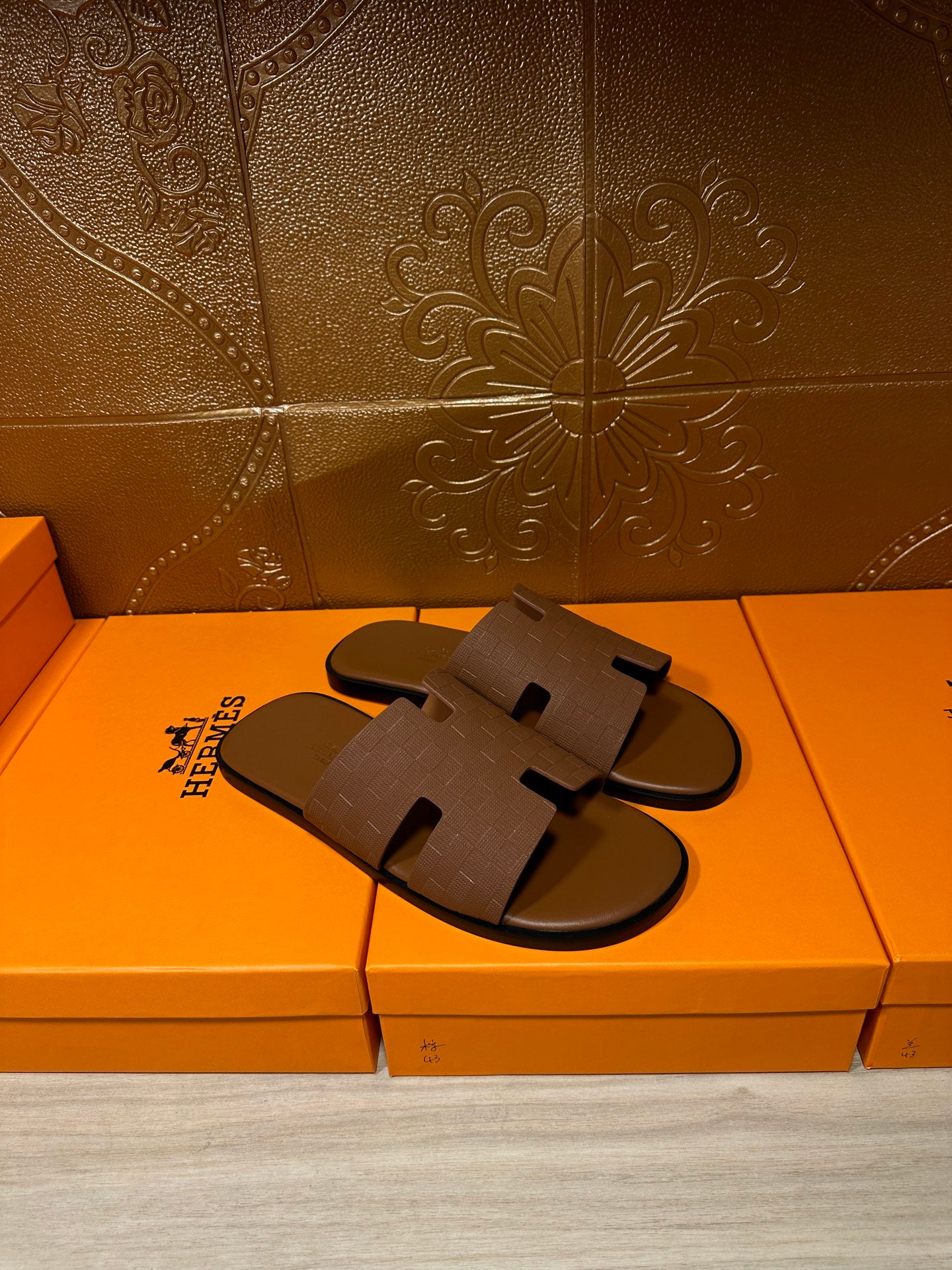 Hermes slide sandals with tan footbed and embossed strap, laid on box