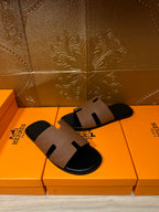 Tan leather slide sandal with black footbed and H-style strap, angled view