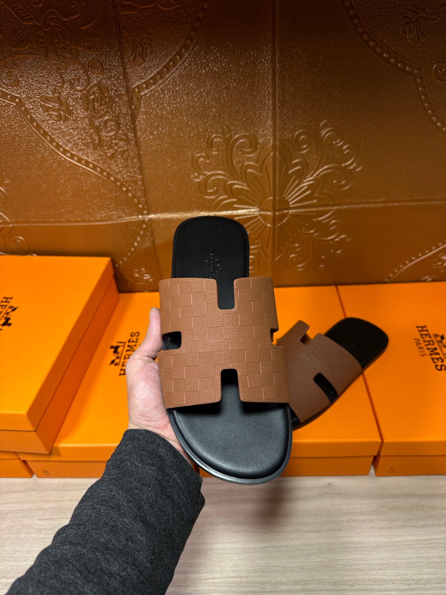 Tan leather slide sandal held up; black rubber sole with H-style strap