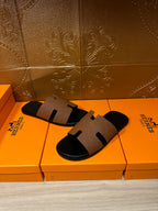 Tan leather slide sandal with black rubber sole and H-style strap, pair view