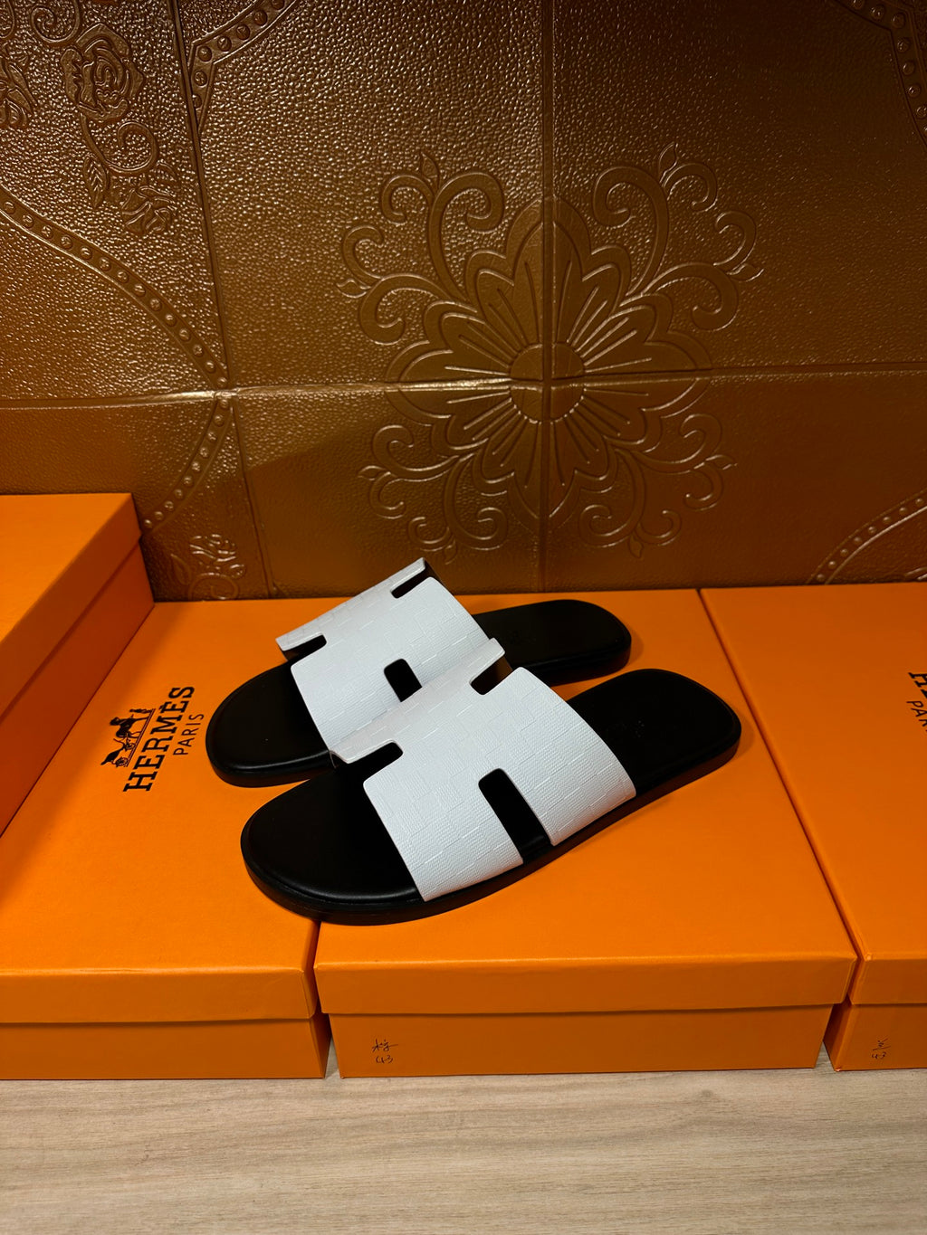 Hermes slide sandals with white textured straps over black footbed, H-cutout design