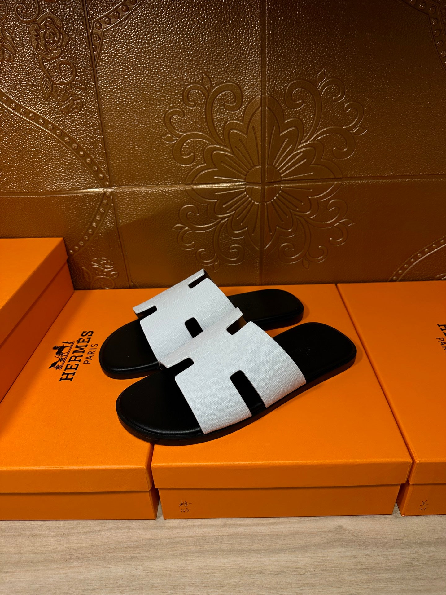 Hermes slide sandals with white textured straps over black footbed, H-cutout design