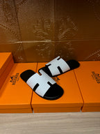 Hermes slide sandals, white and black with H-cutout straps, angled side view