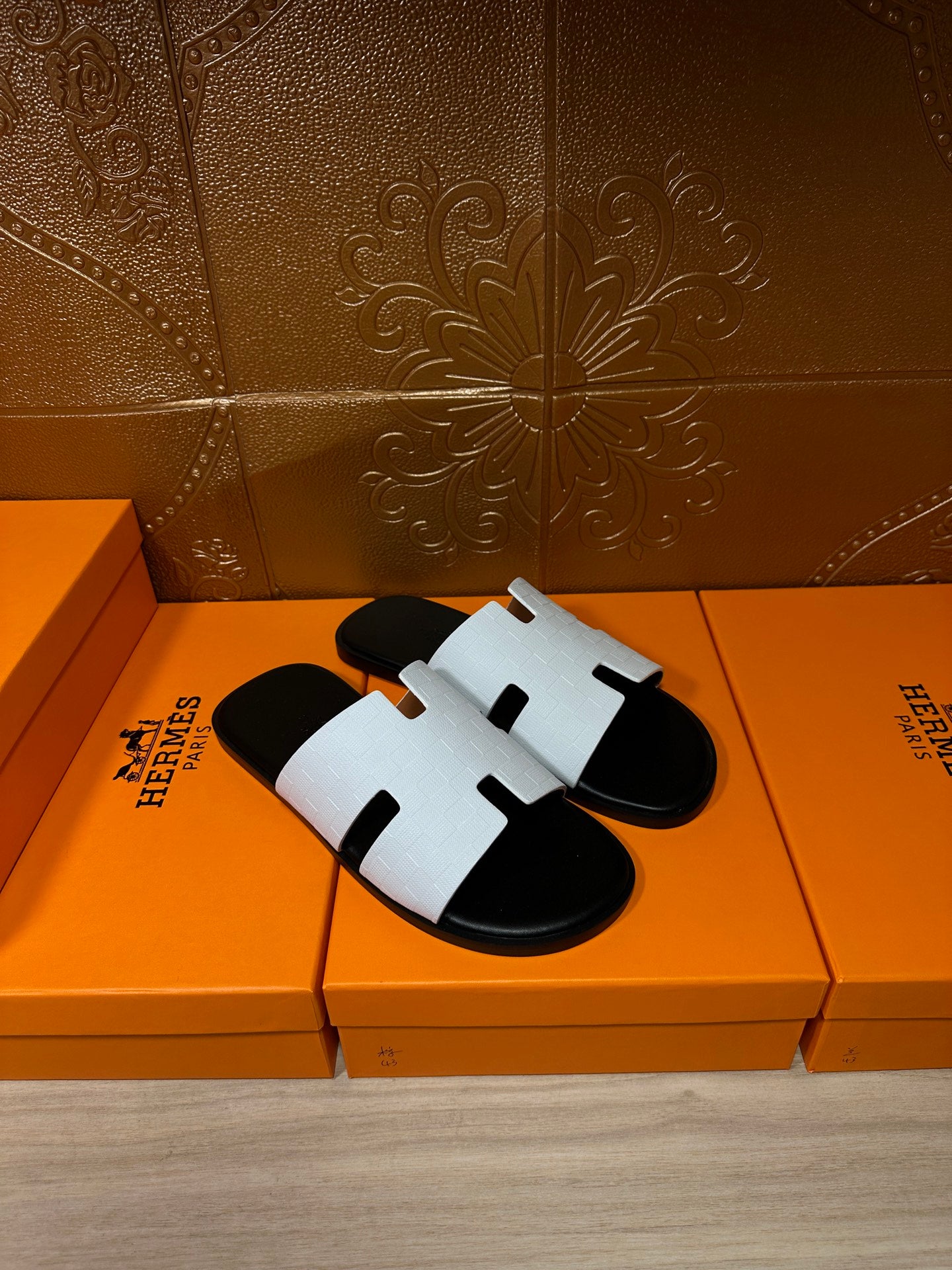 Hermes slide sandals pair with white straps on black footbeds, H-cutout detail