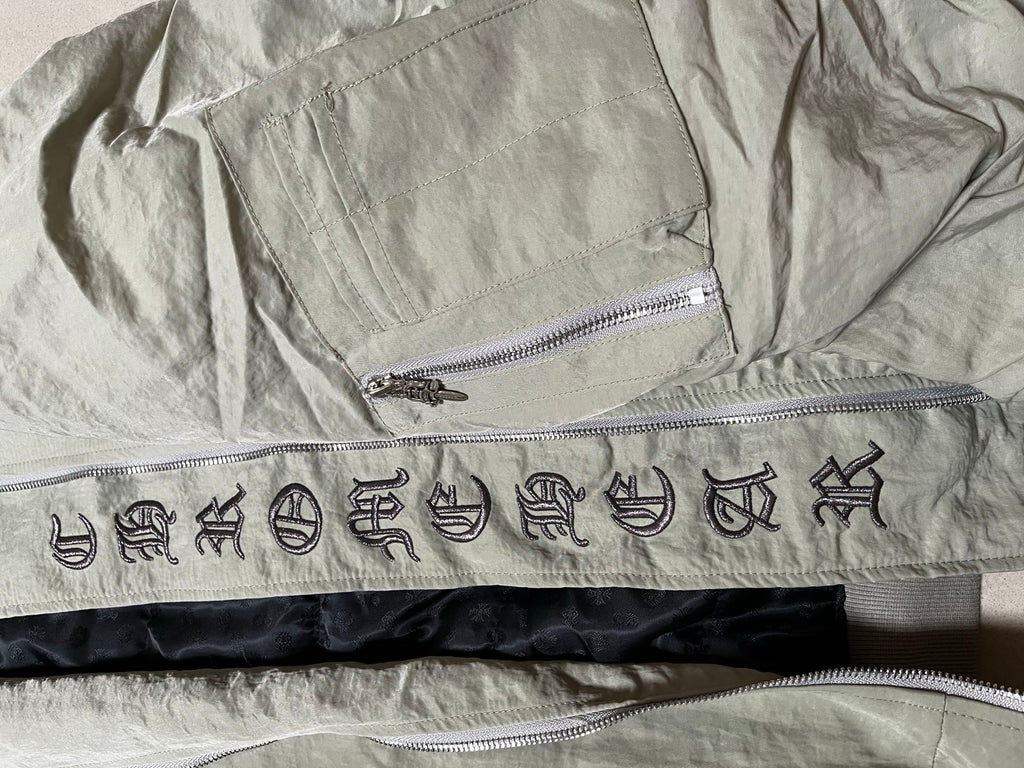 Olive green jacket inner waistband with decorative symbols and two zippers