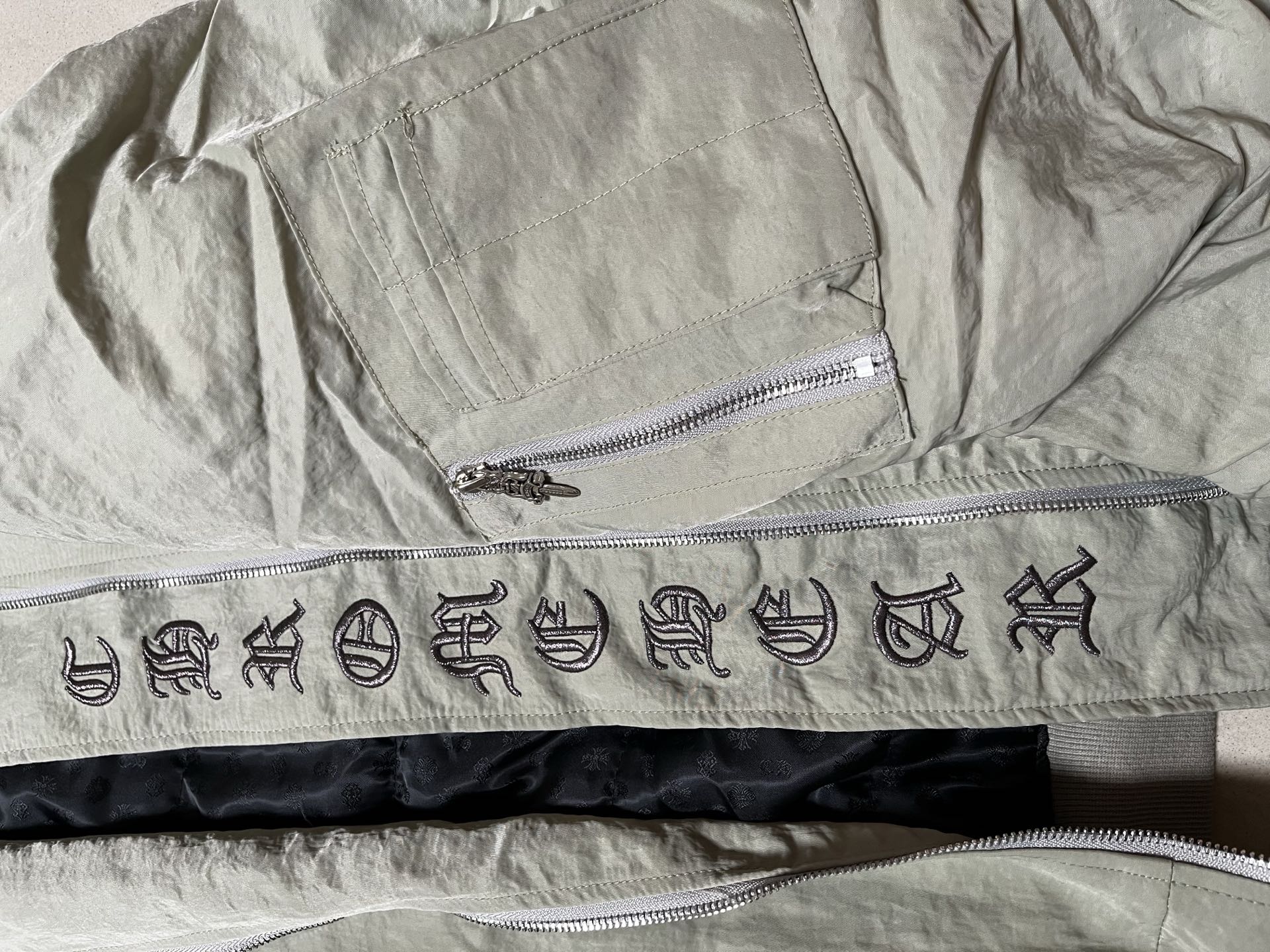 Olive green jacket inner waistband with decorative symbols and two zippers