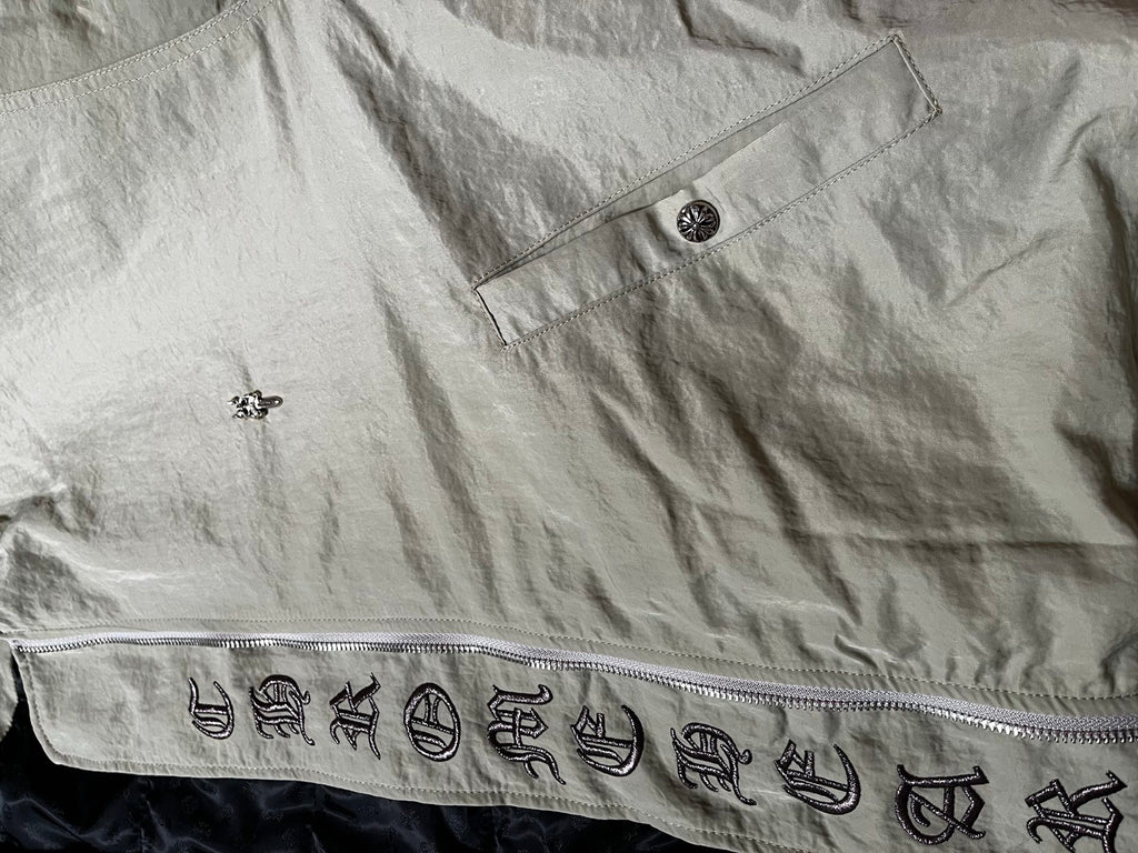 Light gray long jacket with button placket and patterned emblem graphic trim