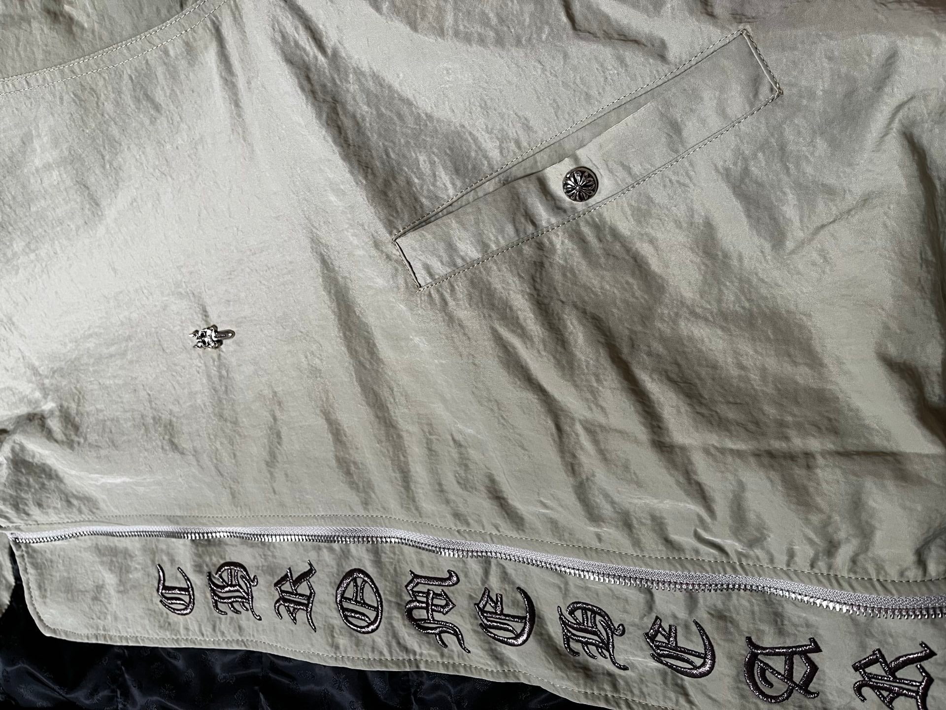 Light gray long jacket with button placket and patterned emblem graphic trim