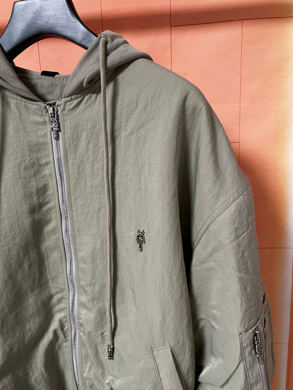 Olive green zip-up hooded jacket with chest pocket and zipper pull detail
