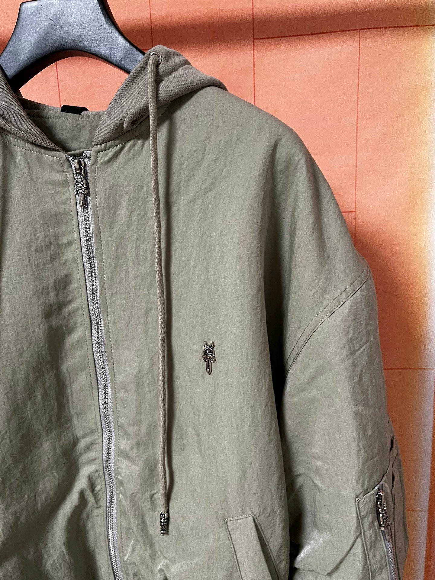 Olive green zip-up hooded jacket with chest pocket and zipper pull detail