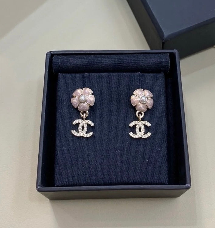 Chanel stud earrings with silver flower tops, faux pearl detail, and CC drop charms