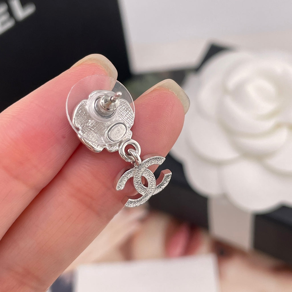 Chanel single drop earring close-up: silver flower stud with faux pearl and CC charm