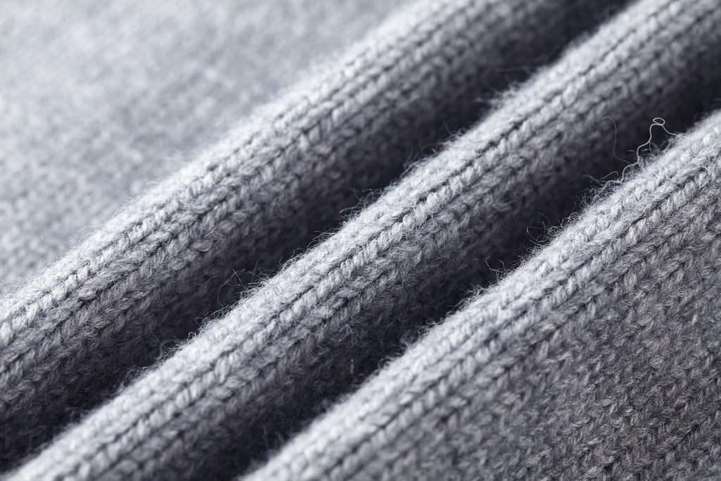 Close-up of gray knit fabric texture and ribbed trim on sweater.