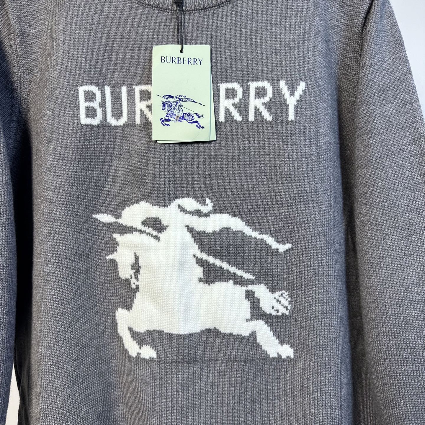 Gray Burberry knit sweater with 'BURBERRY' text and white horse emblem