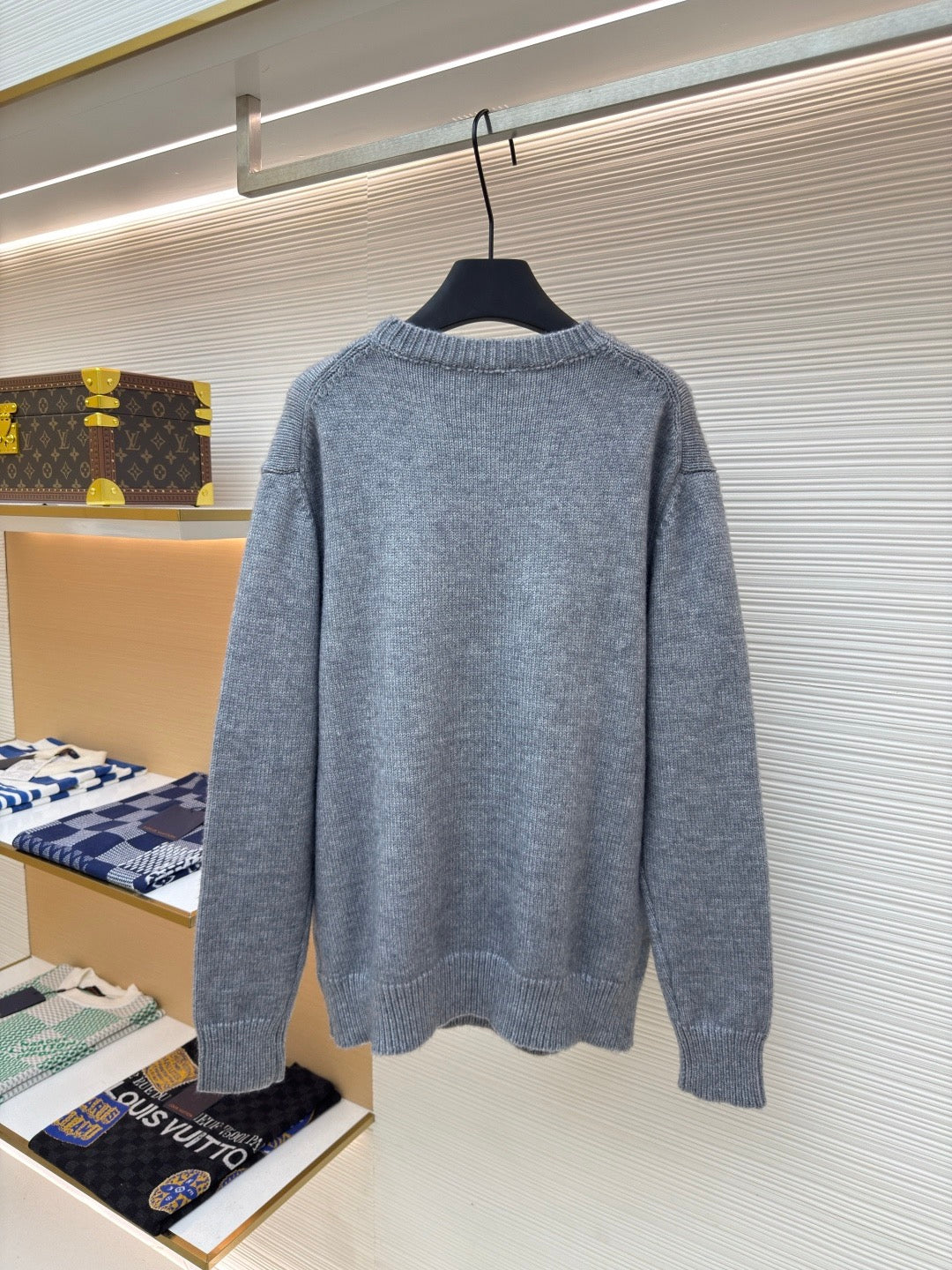 Gray crewneck knit sweater, long sleeves, plain back view on hanger.