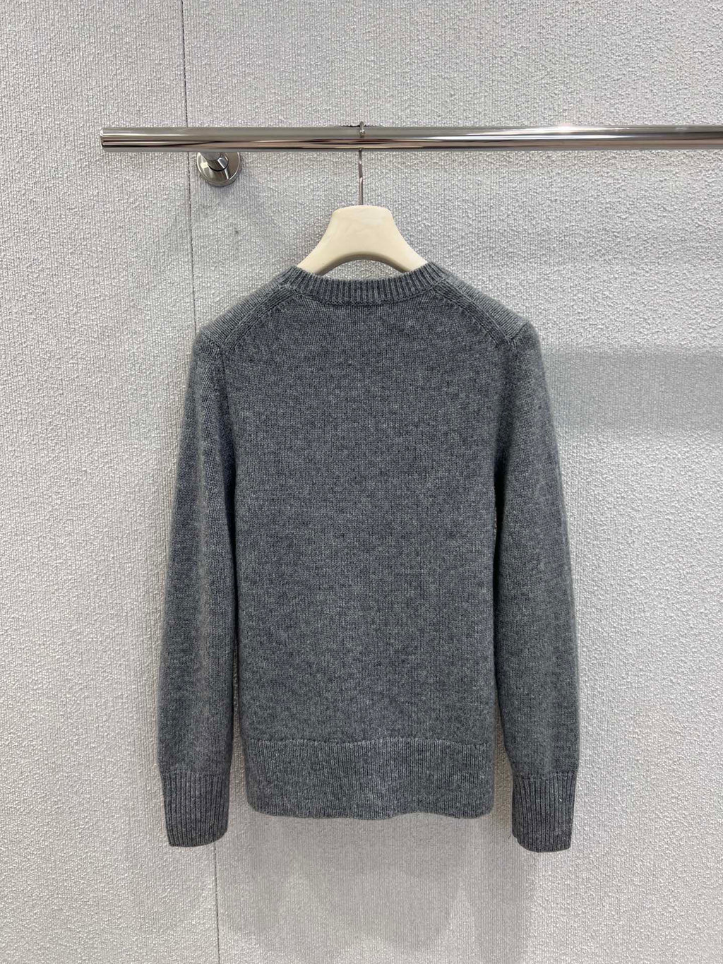 Gray crewneck knit sweater with long sleeves, ribbed cuffs and hem, on hanger.