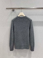 Gray crewneck knit sweater with long sleeves, ribbed cuffs and hem, on hanger.