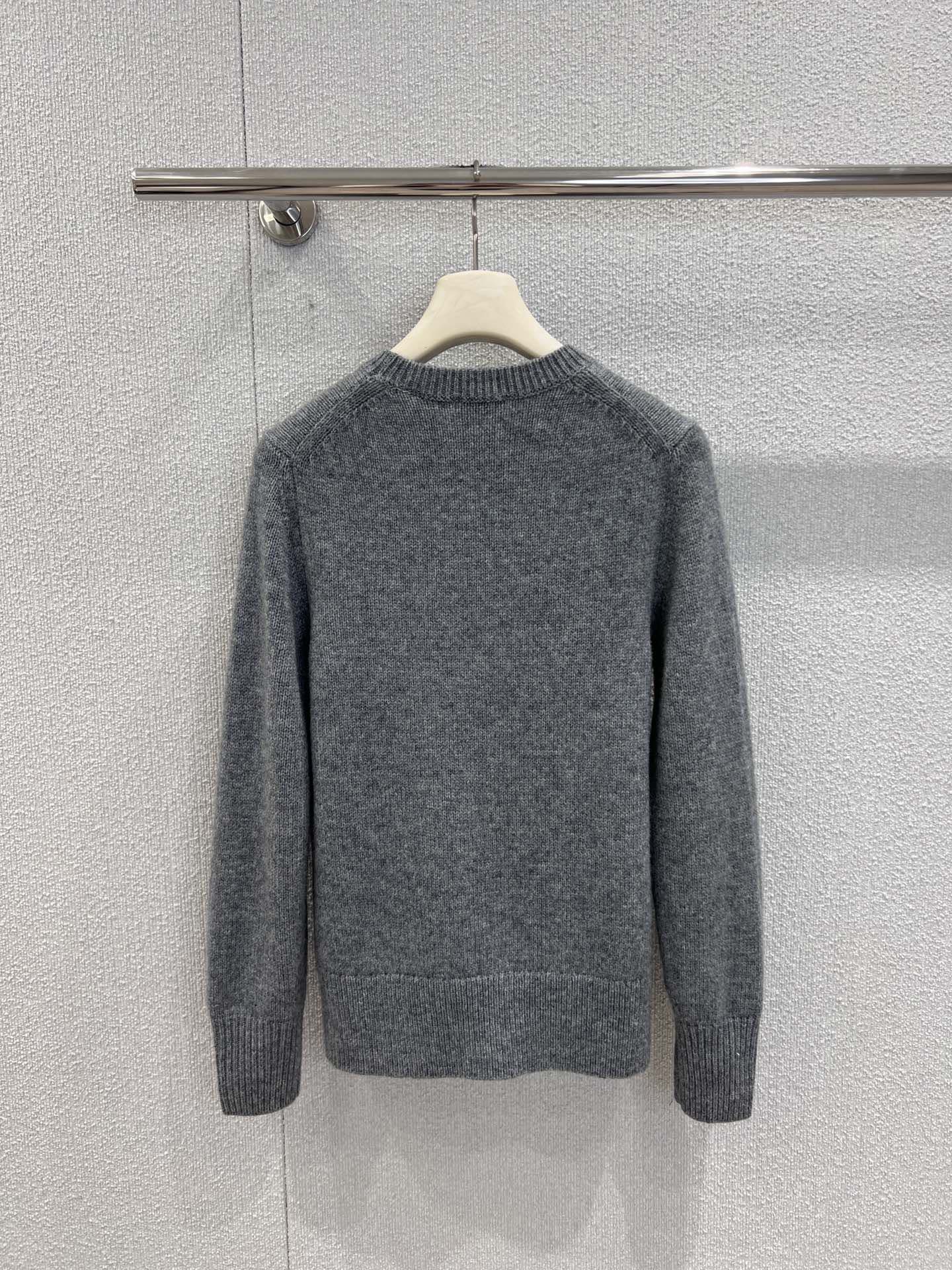 Gray crewneck knit sweater with long sleeves, ribbed cuffs and hem, on hanger.