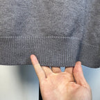 Gray knit sweater fabric close-up with ribbed hem edge