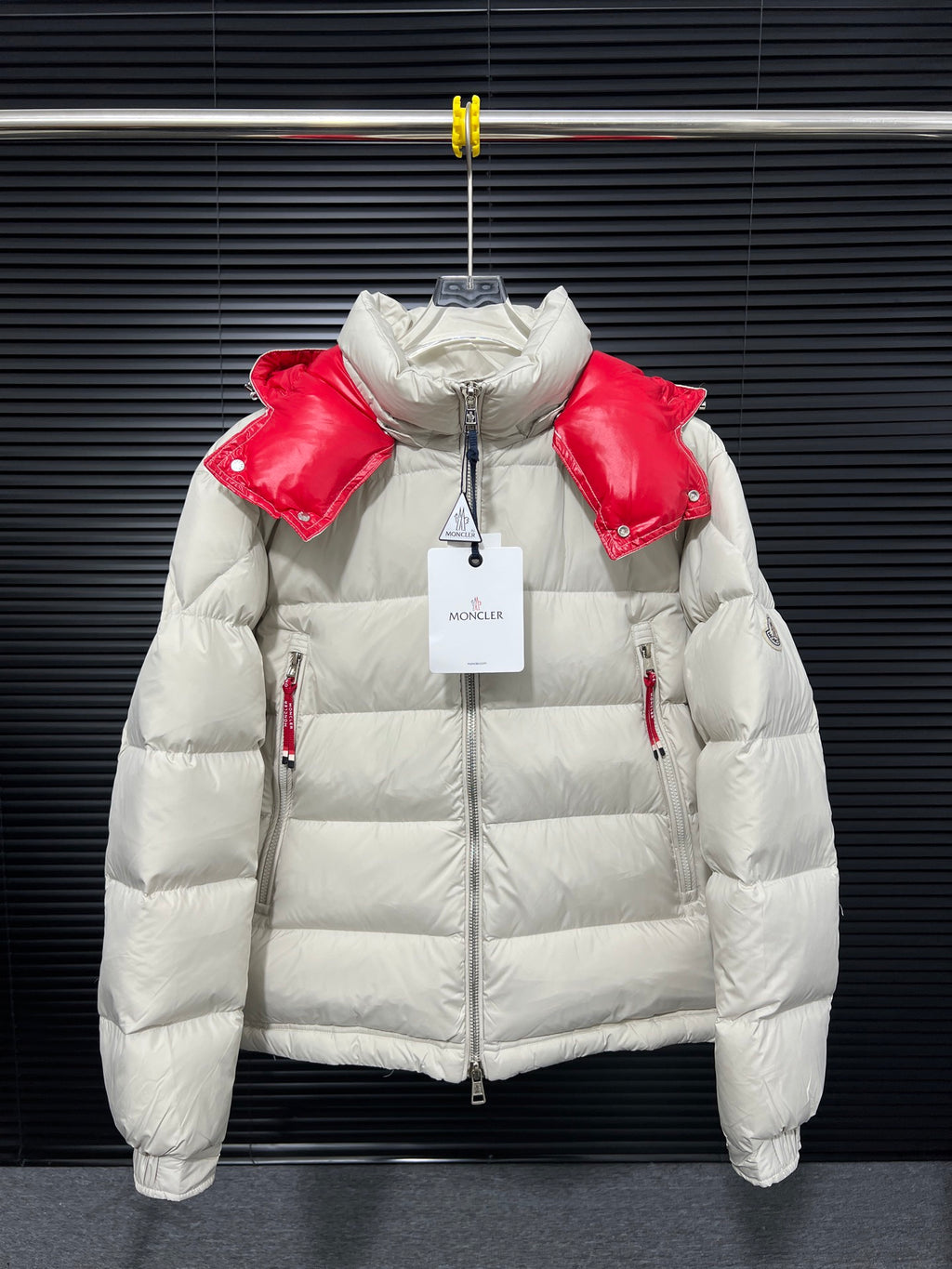 Long white puffer jacket with red shoulder panels and zip front, hood up