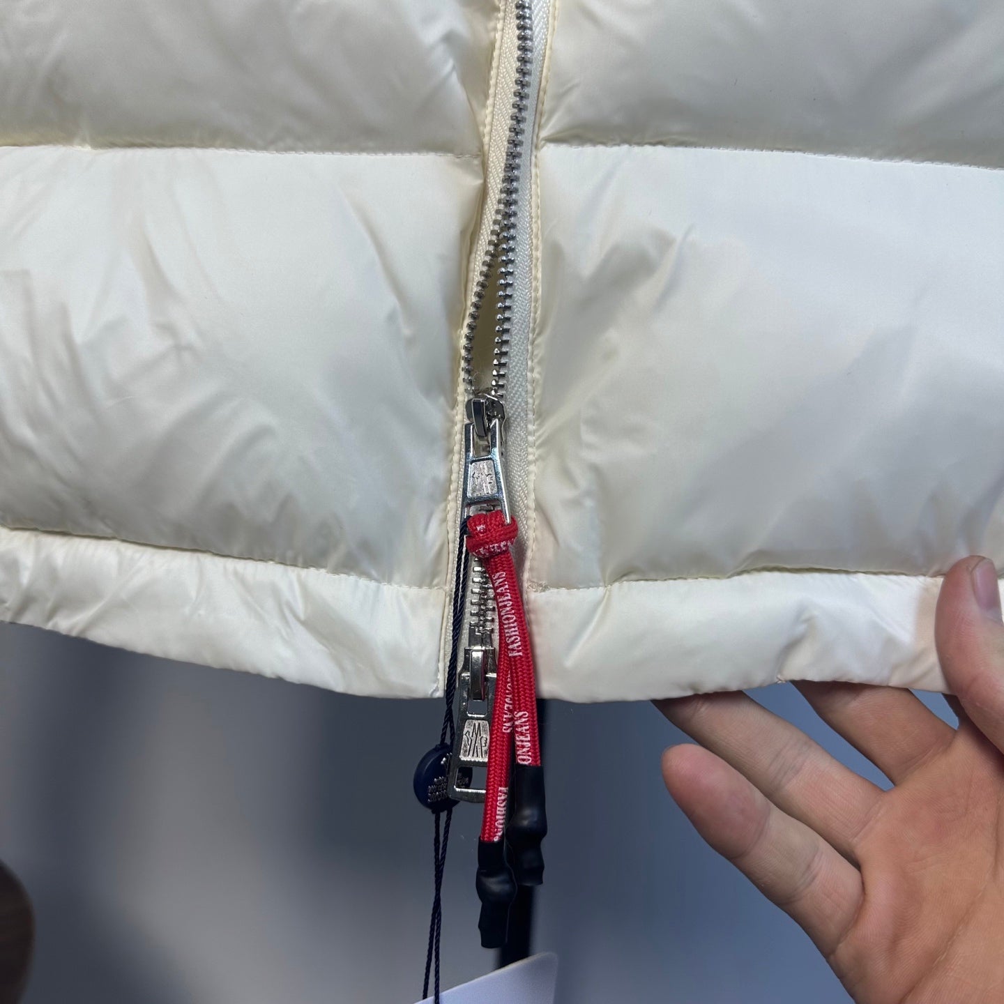 Moncler long puffer jacket zipper close-up with red pull and metal slider