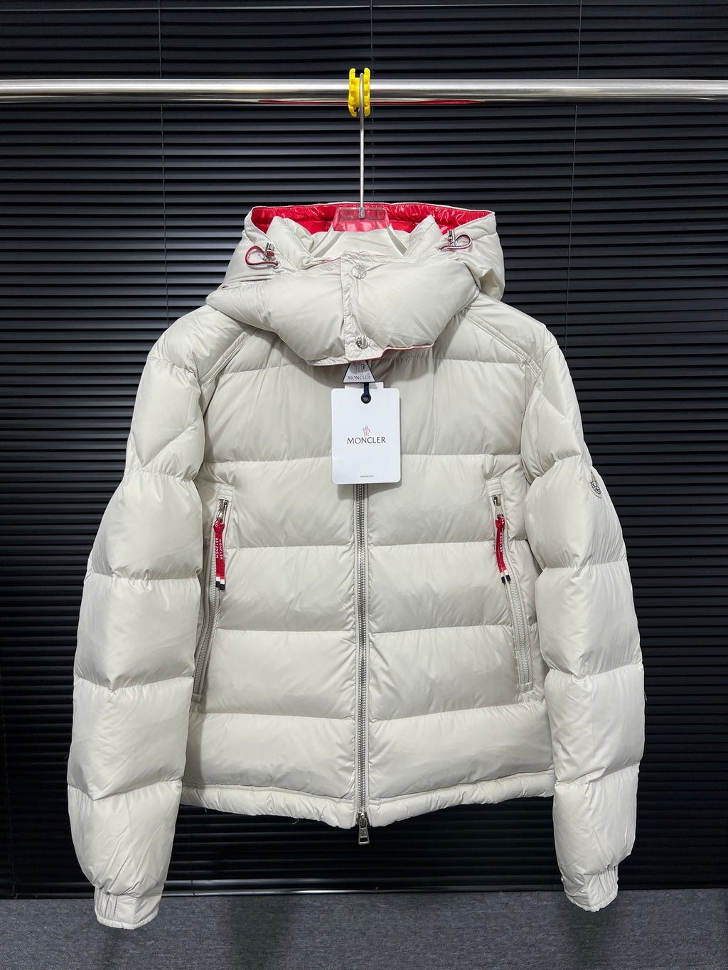 Long white puffer jacket with red inner hood, zip front, and quilted shoulders