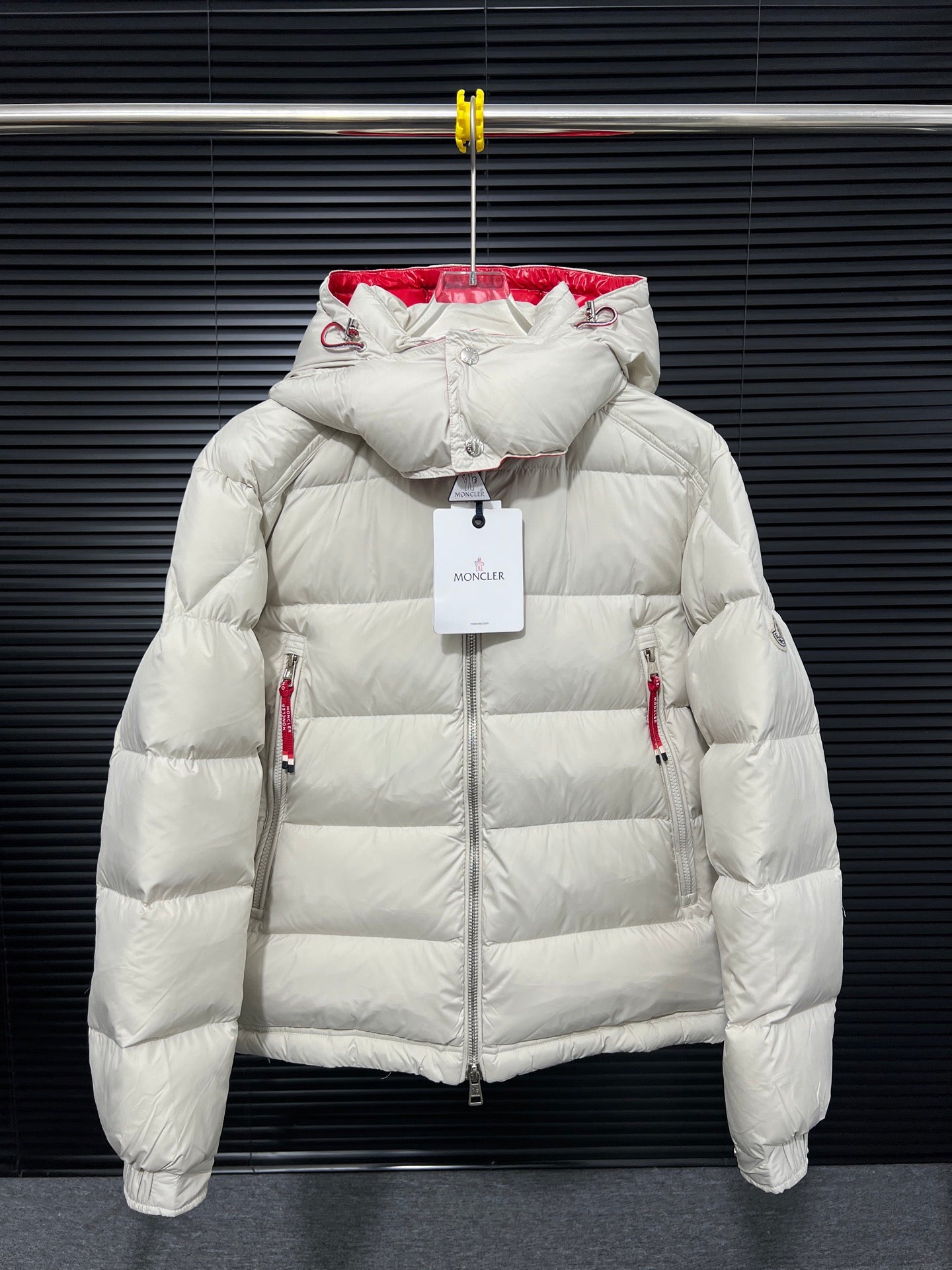 Long white puffer jacket with red inner hood, zip front, and quilted shoulders