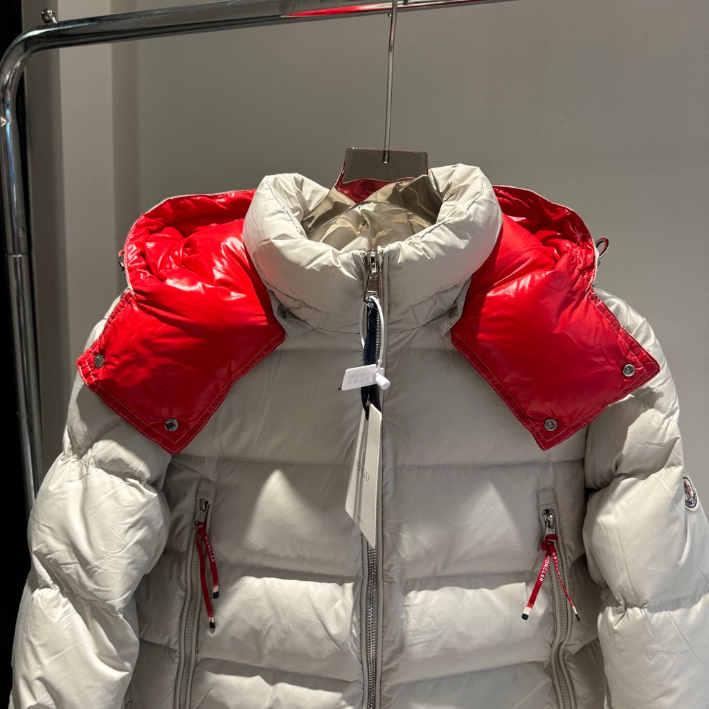 Long white puffer jacket with red collar, full-zip front, drawcord hood, and side zips
