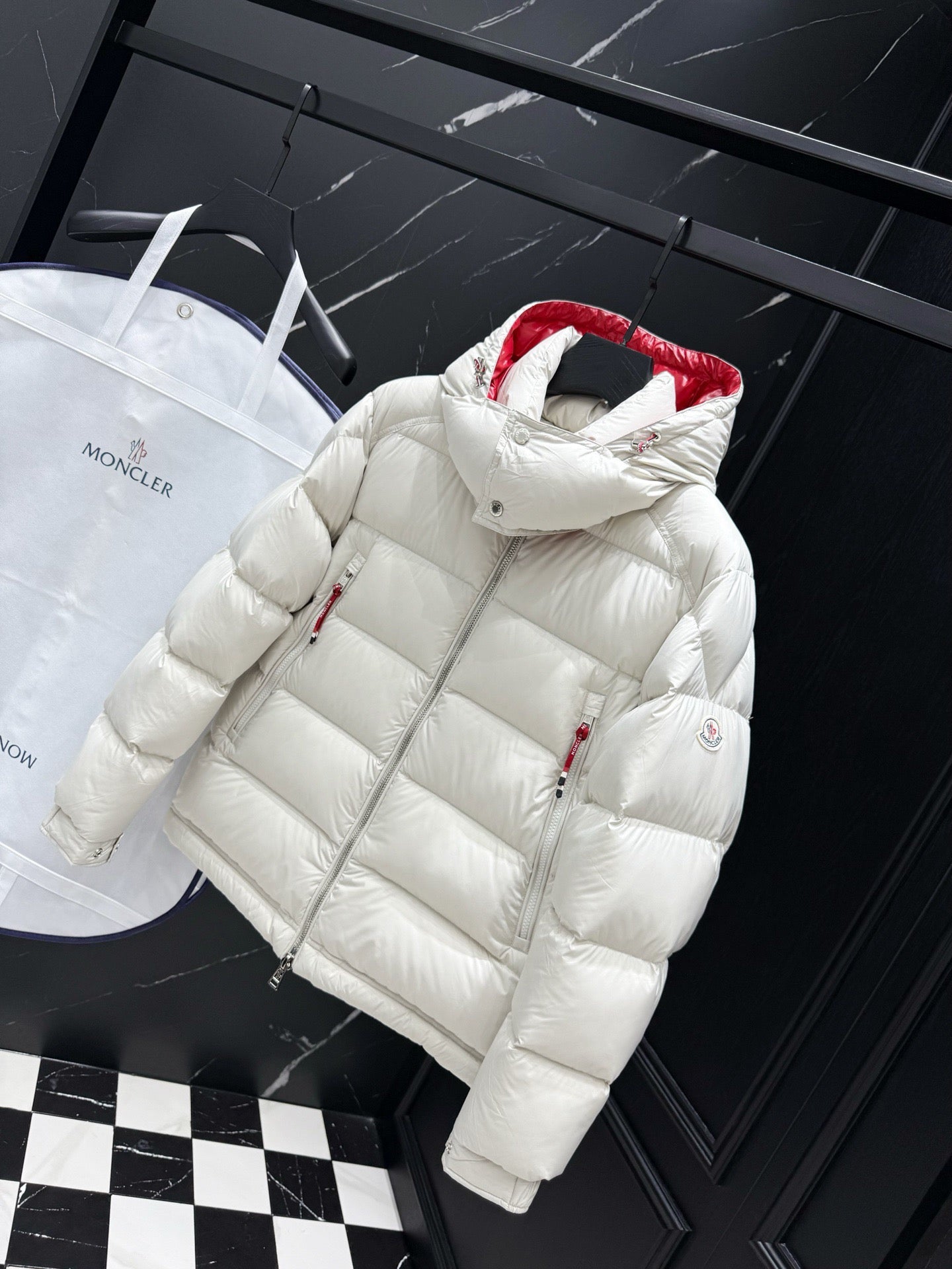 White long puffer jacket with quilted panels, red hood lining, and zip closure