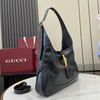 Black leather hobo bag, side view with shoulder strap and gold-tone front clasp