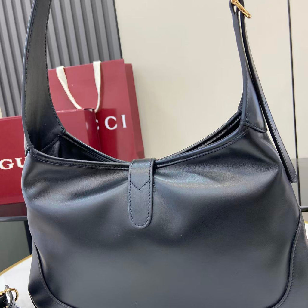 Gucci bag in dark leather with curved strap and front seam, single top handle.