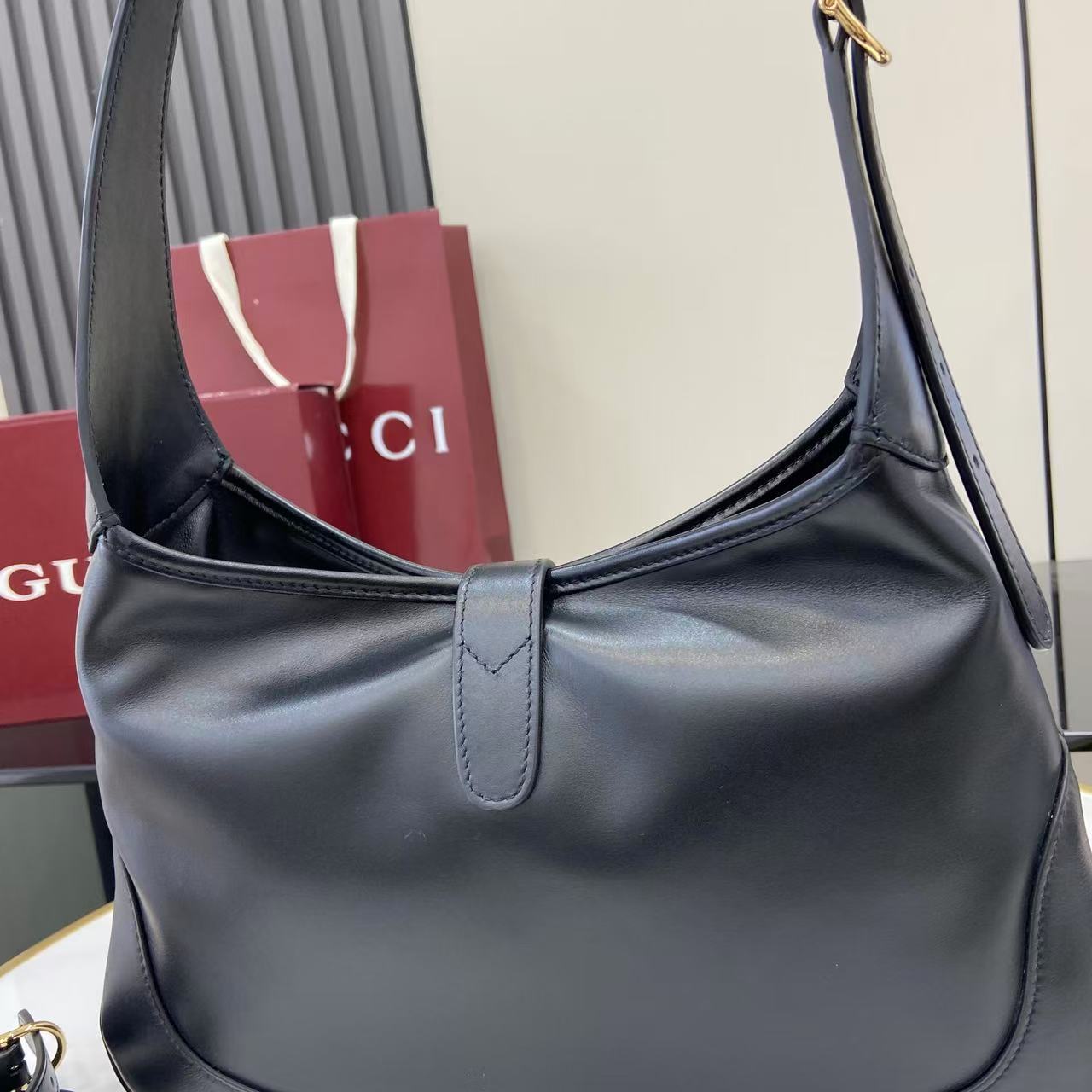 Gucci bag in dark leather with curved strap and front seam, single top handle.