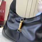 Black leather hobo bag front detail with gold-tone clasp and stitched accent panel